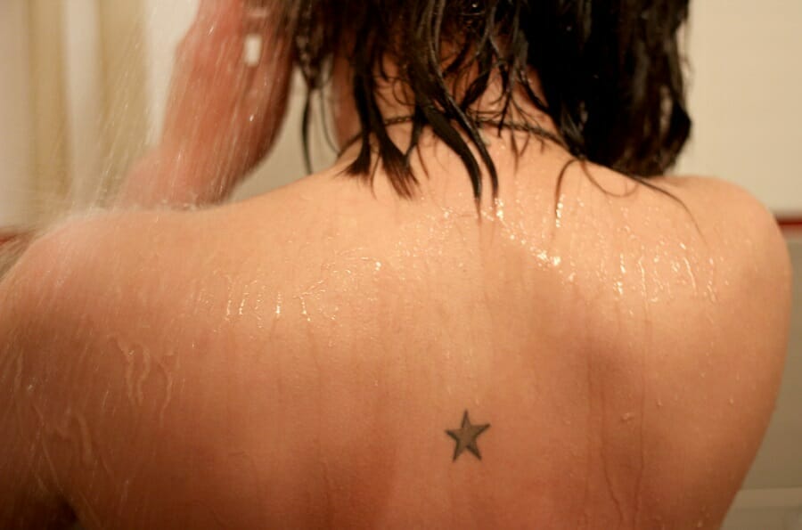 Shower water on skin of woman with star tattoo on back